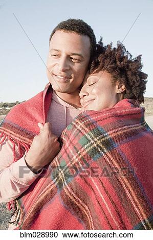 Couple wrapped in blanket on beach View Large Photo Image Stock Image - Couple wrapped in blanket on beach. Fotosearch