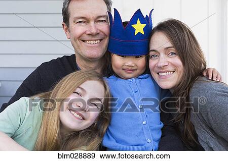 Family smiling together outside house View Large Photo Image Stock Photo - Family smiling together outside house. Fotosearch