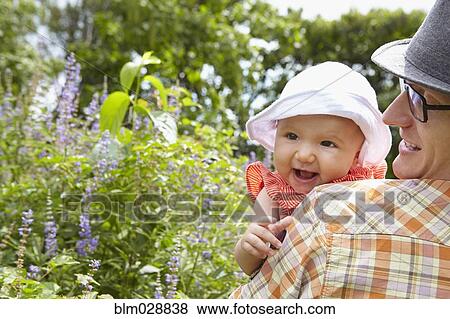 Stock Photo - Father carrying baby daughter in park. Fotosearch