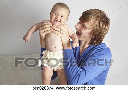 Picture - Father holding baby on bed. Fotosearch