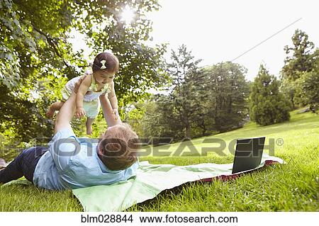 Picture - Father playing with baby girl in park. Fotosearch