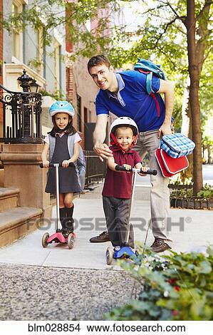 Picture - Father taking children on scooters to school. Fotosearch