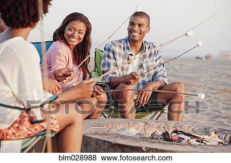 Friends roasting marshmallows on beach View Large Photo Image Stock Photo - Friends roasting marshmallows on beach. Fotosearch