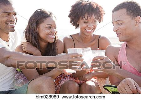 Friends toasting each other on beach View Large Photo Image Stock Photo - Friends toasting each other on beach. Fotosearch