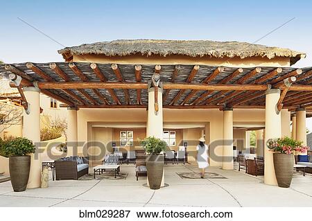 Stock Photo - Hispanic woman on modern patio of resort. Fotosearch