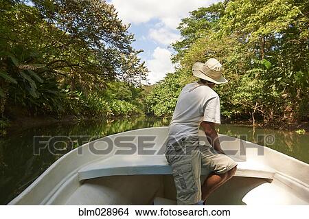 Picture - Middle Eastern man in boat on rural river. Fotosearch