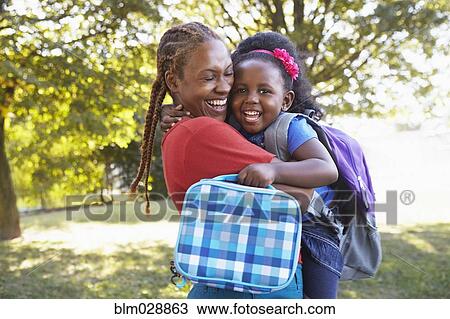 Stock Image - Mixed race mother and hugging daughter. Fotosearch