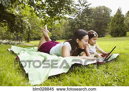 Mother and baby girl using laptop in park View Large Photo Image Stock Photography - Mother and baby girl using laptop in park. Fotosearch