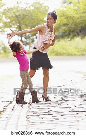 Stock Photograph - Mother and daughter posing on city street. Fotosearch