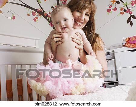 Stock Image - Mother holding baby girl in tutu. Fotosearch