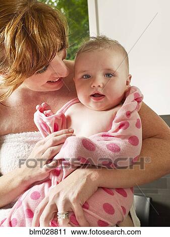 Stock Image - Mother wrapping baby girl in towel. Fotosearch
