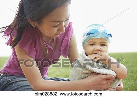 Mother wrapping baby in towel outdoors View Large Photo Image Stock Image - Mother wrapping baby in towel outdoors. Fotosearch