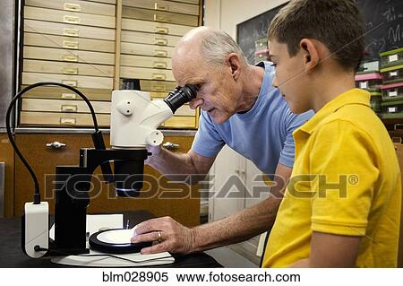Stock Photography - Teacher and student using microscope in laboratory. Fotosearch
