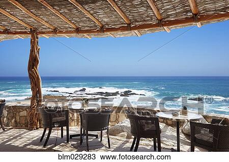 Stock Image - Thatched roof and patio overlooking ocean, Cabo San Lucas, BCS, Mexico. Fotosearch