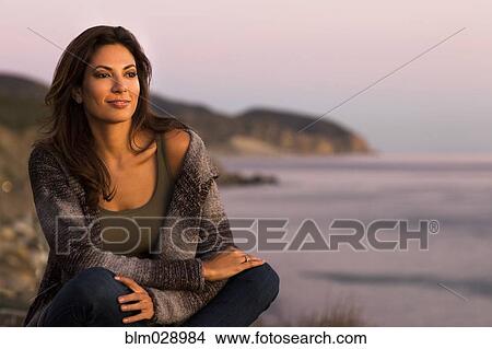 Picture - Woman wrapped in sweater on beach. Fotosearch