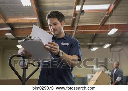 Worker reading clipboard in warehouse View Large Photo Image Stock Image - Worker reading clipboard in warehouse. Fotosearch