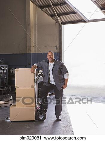 Worker with boxes on hand truck in warehouse View Large Photo Image Stock Image - Worker with boxes on hand truck in warehouse. Fotosearch