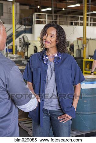 Stock Photography - Workers shaking hands in warehouse. Fotosearch