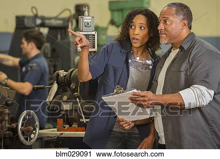 Stock Image - Workers talking in warehouse. Fotosearch