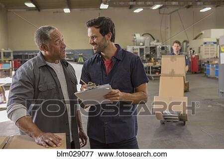 Stock Photo - Workers talking in warehouse. Fotosearch