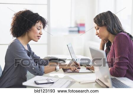 Stock Image - African American businesswomen talking in meeting. Fotosearch