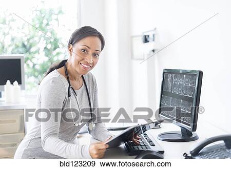 African American doctor holding clipboard in office View Large Photo Image Stock Photo - African American doctor holding clipboard in office. Fotosearch