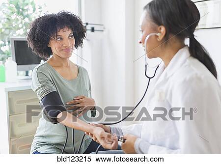 Stock Photography - African American doctor taking pregnant woman's blood pressure. Fotosearch