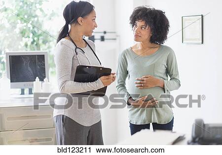 Stock Image - African American doctor talking to pregnant woman. Fotosearch