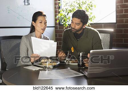 Stock Photography - Business people working over lunch. Fotosearch