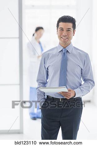 Stock Image - Businessman smiling in hospital. Fotosearch