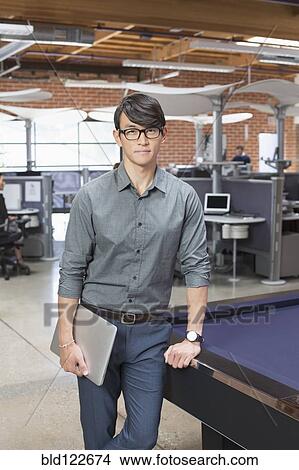Businessman standing in office lounge area View Large Photo Image Picture - Businessman standing in office lounge area. Fotosearch