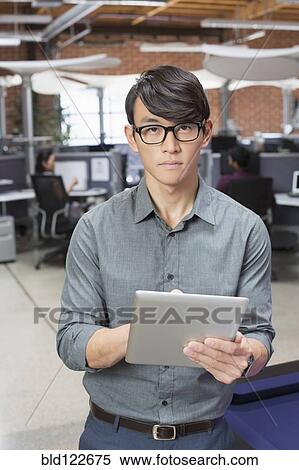 Businessman using digital tablet in office lounge area View Large Photo Image Stock Photography - Businessman using digital tablet in office lounge area. Fotosearch