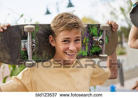 Stock Photo - Caucasian boy holding skateboard outdoors. Fotosearch