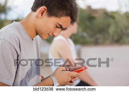 Caucasian boy using cell phone outdoors View Large Photo Image Stock Photo - Caucasian boy using cell phone outdoors. Fotosearch