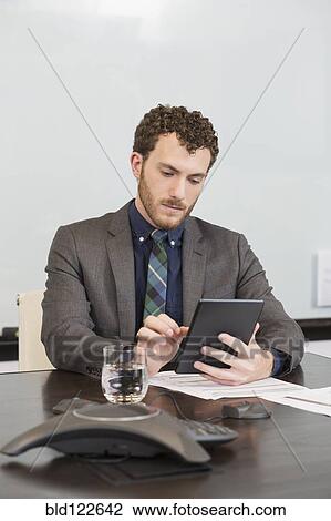 Stock Image - Caucasian businessman using digital tablet in office. Fotosearch