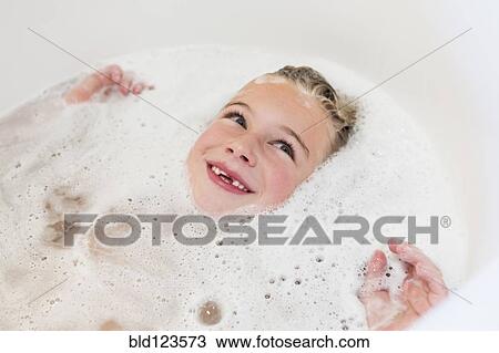 Stock Image - Caucasian girl laying in bubble bath. Fotosearch