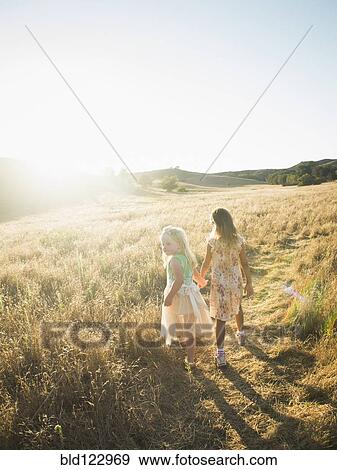 Stock Photo - Caucasian girls holding hands in rural field. Fotosearch