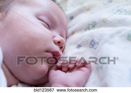 Stock Photo - Caucasian newborn sleeping on bed. Fotosearch