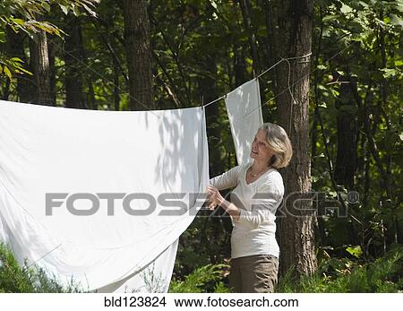 Caucasian woman hanging sheets outdoors View Large Photo Image Picture - Caucasian woman hanging sheets outdoors. Fotosearch