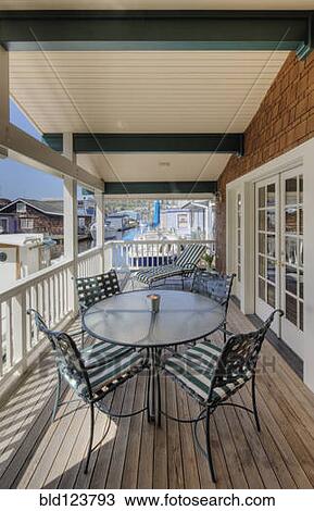 Stock Image - Chairs and table on wooden patio. Fotosearch