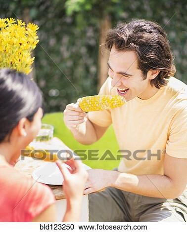 Couple eating corn on the cob outdoors View Large Photo Image Stock Image - Couple eating corn on the cob outdoors. Fotosearch