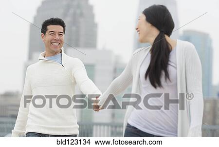 Couple holding hands in city View Large Photo Image Picture - Couple holding hands in city. Fotosearch