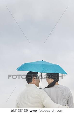 Stock Photo - Couple hugging under umbrella. Fotosearch