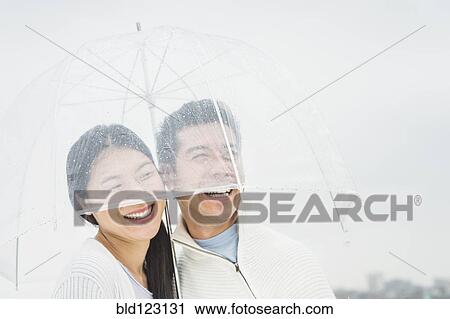 Stock Image - Couple laughing under umbrella. Fotosearch