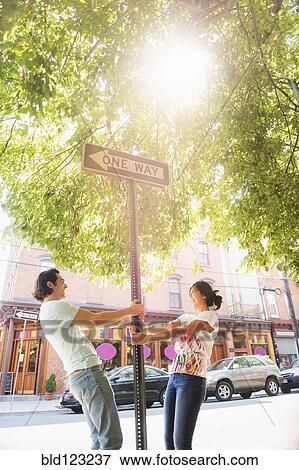 Couple leaning on one way street sign View Large Photo Image Stock Photo - Couple leaning on one way street sign. Fotosearch