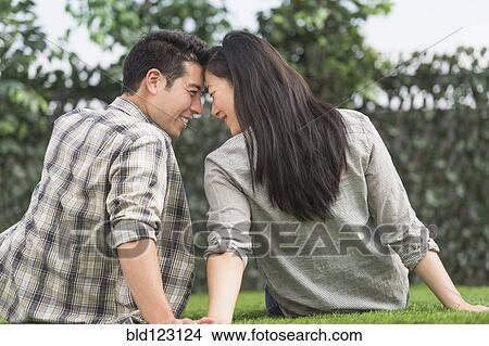 Couple relaxing together in grass View Large Photo Image Picture - Couple relaxing together in grass. Fotosearch