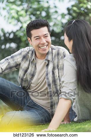 Couple relaxing together in grass View Large Photo Image Stock Photograph - Couple relaxing together in grass. Fotosearch