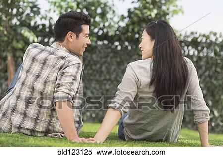 Couple relaxing together in grass View Large Photo Image Stock Photography - Couple relaxing together in grass. Fotosearch