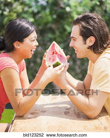 Couple sharing watermelon slice outdoors View Large Photo Image Stock Image - Couple sharing watermelon slice outdoors. Fotosearch
