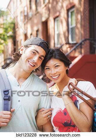 Stock Photo - Couple smiling outside brownstones. Fotosearch